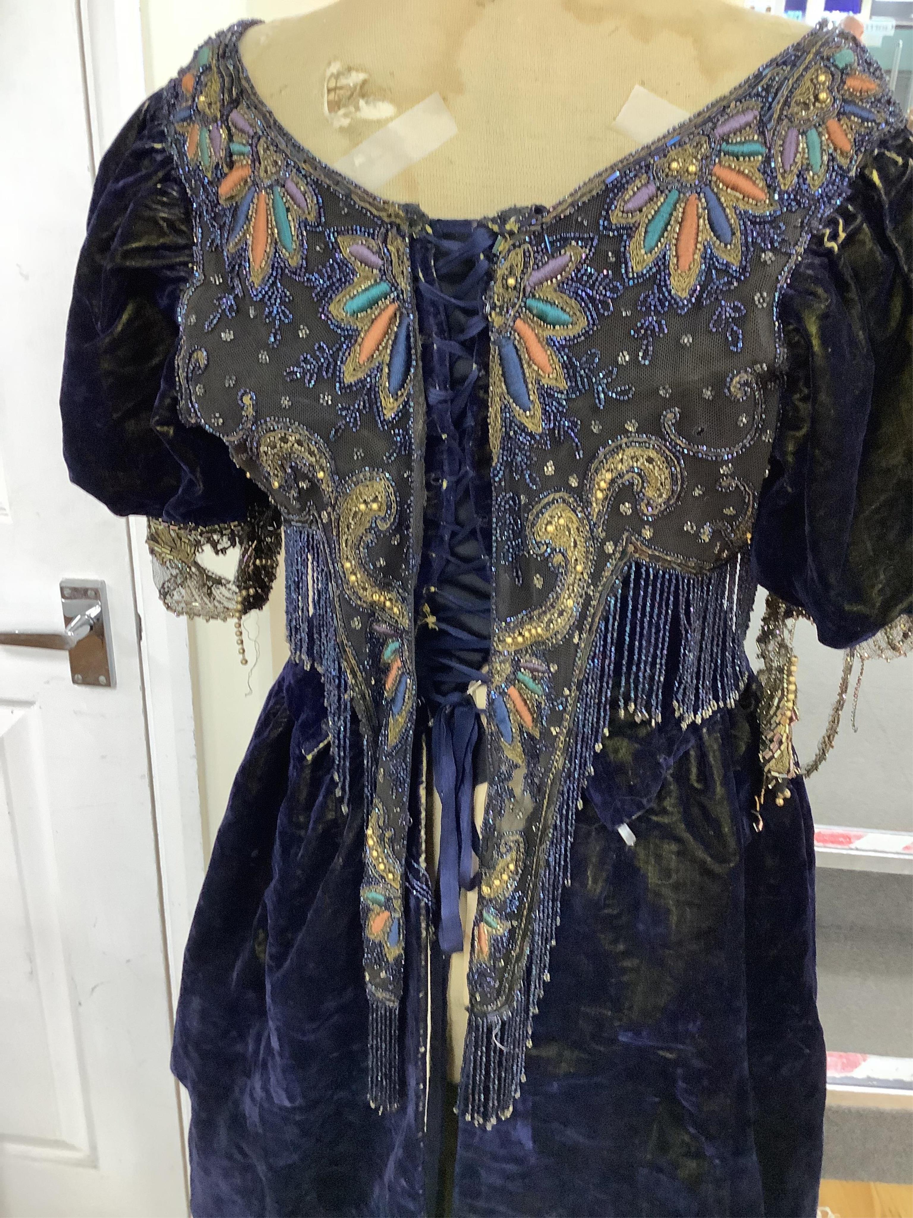 A 19th century ladies silk velvet matching long sleeved jacket/bodice, and skirt, together with another matching short sleeved bead worked bodice and white feather headdress.(4). Cape 106cm long. Condition - Both bodices